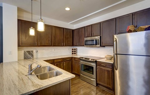 A kitchen with a stainless steel refrigerator, sink, and cabinets.