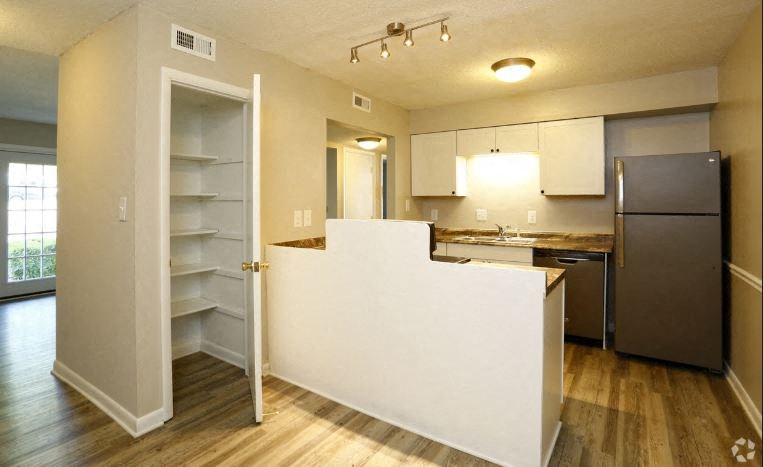 an empty kitchen with a white counter and a refrigerator