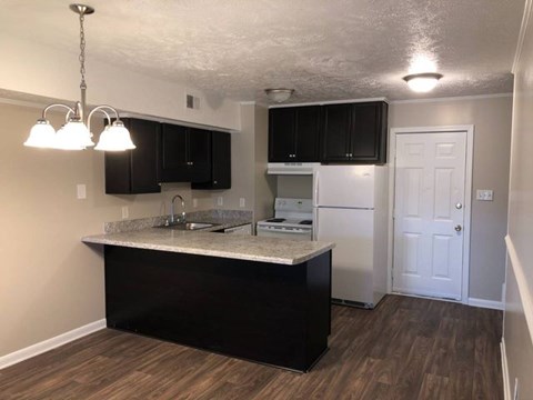 A kitchen with black cabinets and a white fridge.