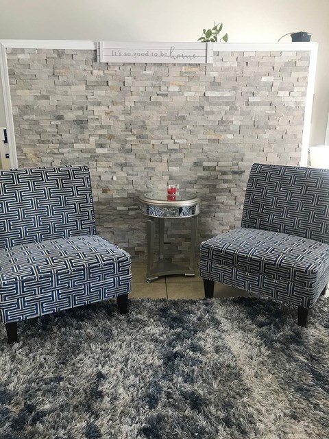 a living room with two chairs and a brick wall