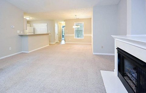 A spacious living room with a fireplace and a carpeted floor.