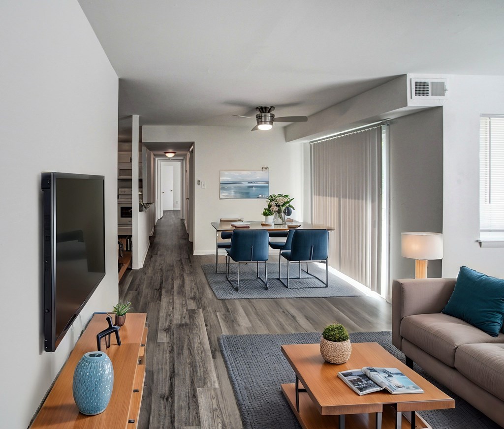 A modern living room with a wooden floor and a flat screen TV mounted on the wall.