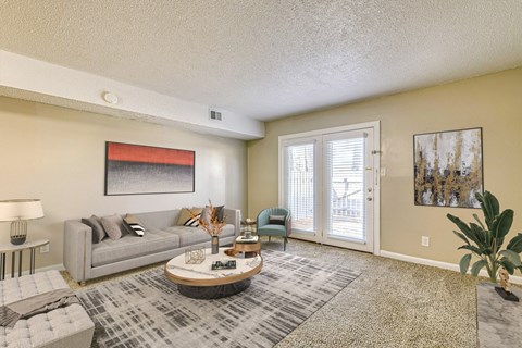 A living room with a grey couch, a coffee table, and a painting on the wall.