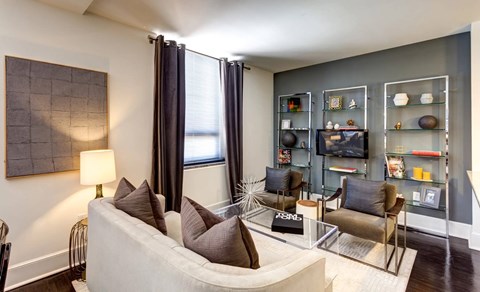 A living room with a white couch and a painting on the wall.