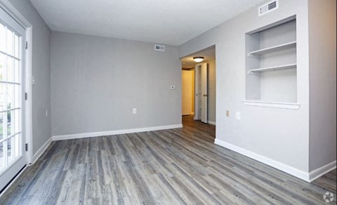 a empty living room with wood floors and white walls