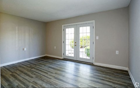 an empty living room with a door and wood floors