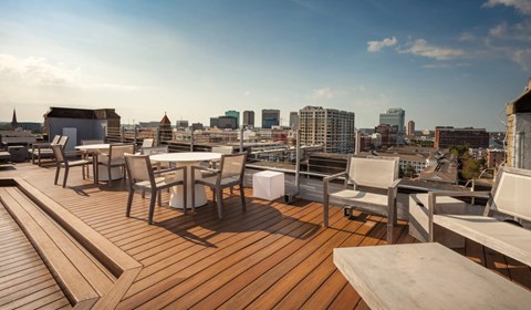 A wooden deck with chairs and a table overlooking a city skyline.