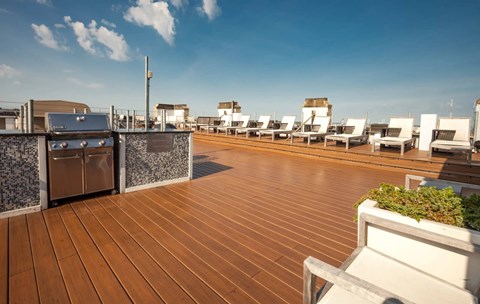 A rooftop patio with wooden flooring and white chairs.