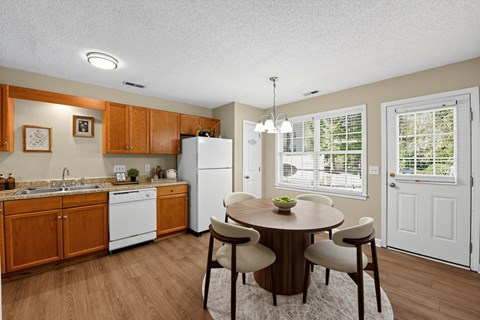 A kitchen with a table and chairs in front of a window.