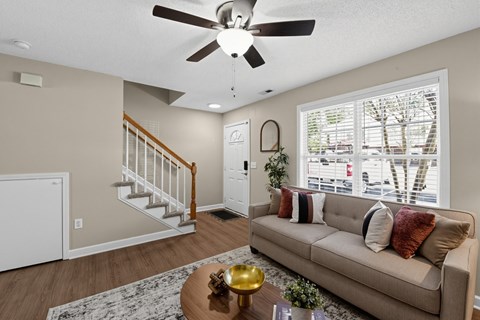 A living room with a couch, coffee table, and a ceiling fan.