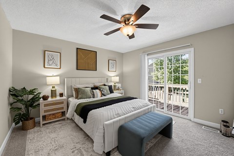 A bedroom with a large bed, a bench, and a ceiling fan.