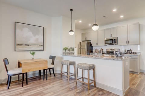 A kitchen with a table and chairs and a framed picture on the wall.