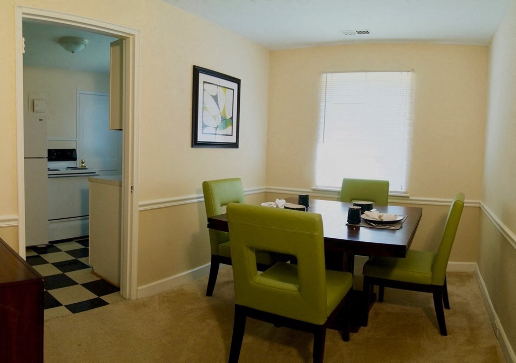 View of dining room model with square table and four green chairs