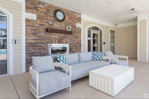 A white couch with grey cushions is placed in front of a brick wall.