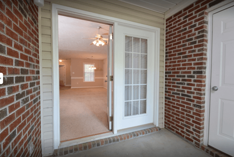 A white door is open to a room with a ceiling fan.