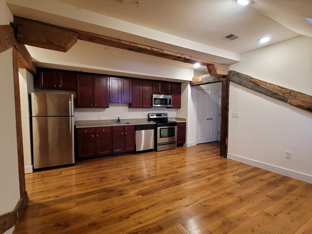 a kitchen with wooden floors and stainless steel appliances
