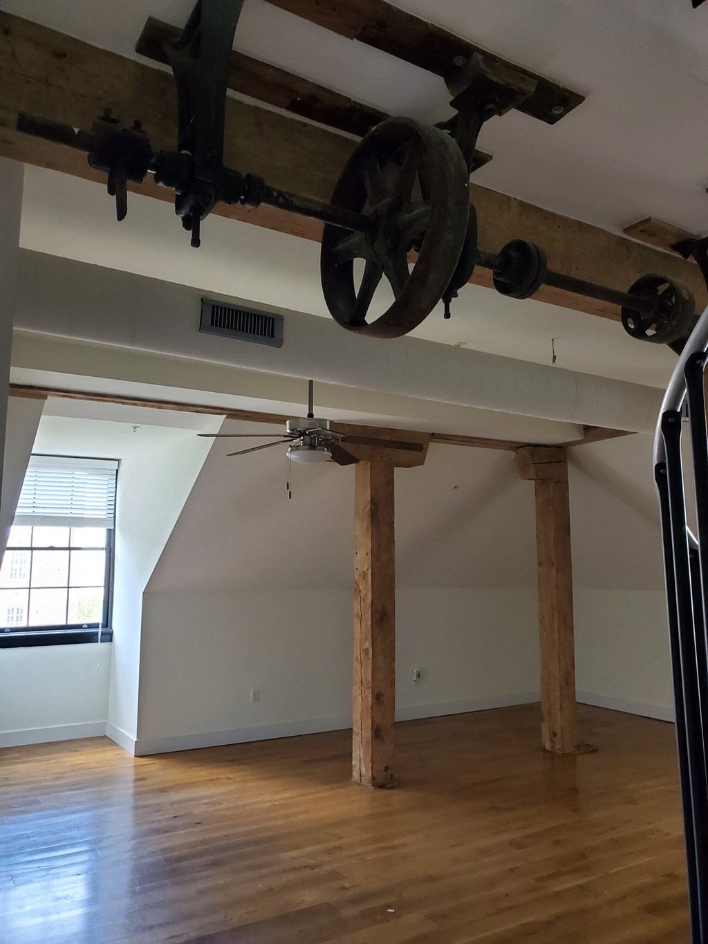 a view of the ceiling of a large room with wooden beams and a ceiling fan