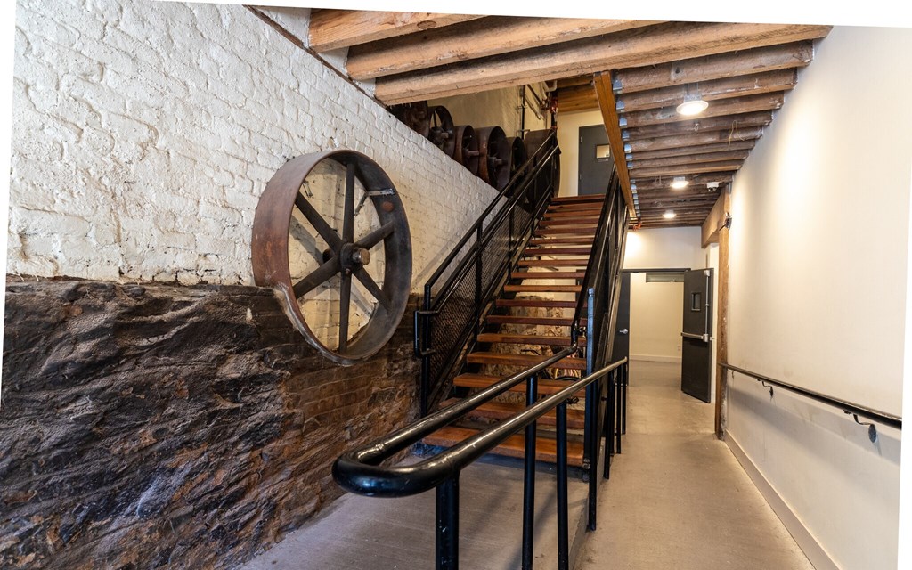 a staircase with a water wheel next to a brick wall