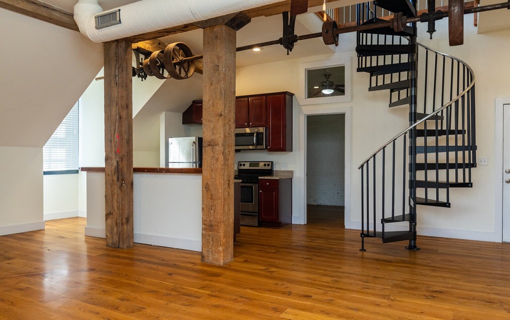 a living room with a staircase and a kitchen in a house