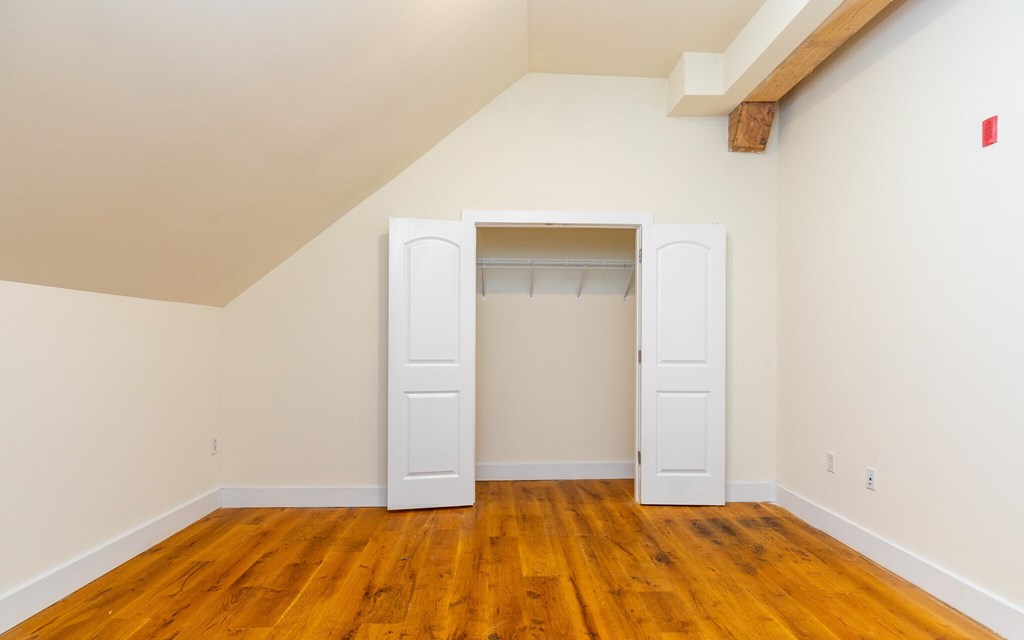 an empty room with wooden floors and a closet with two doors
