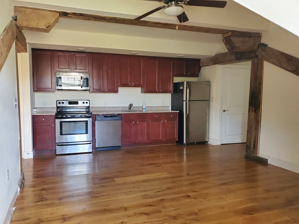 an empty kitchen with wooden floors and stainless steel appliances