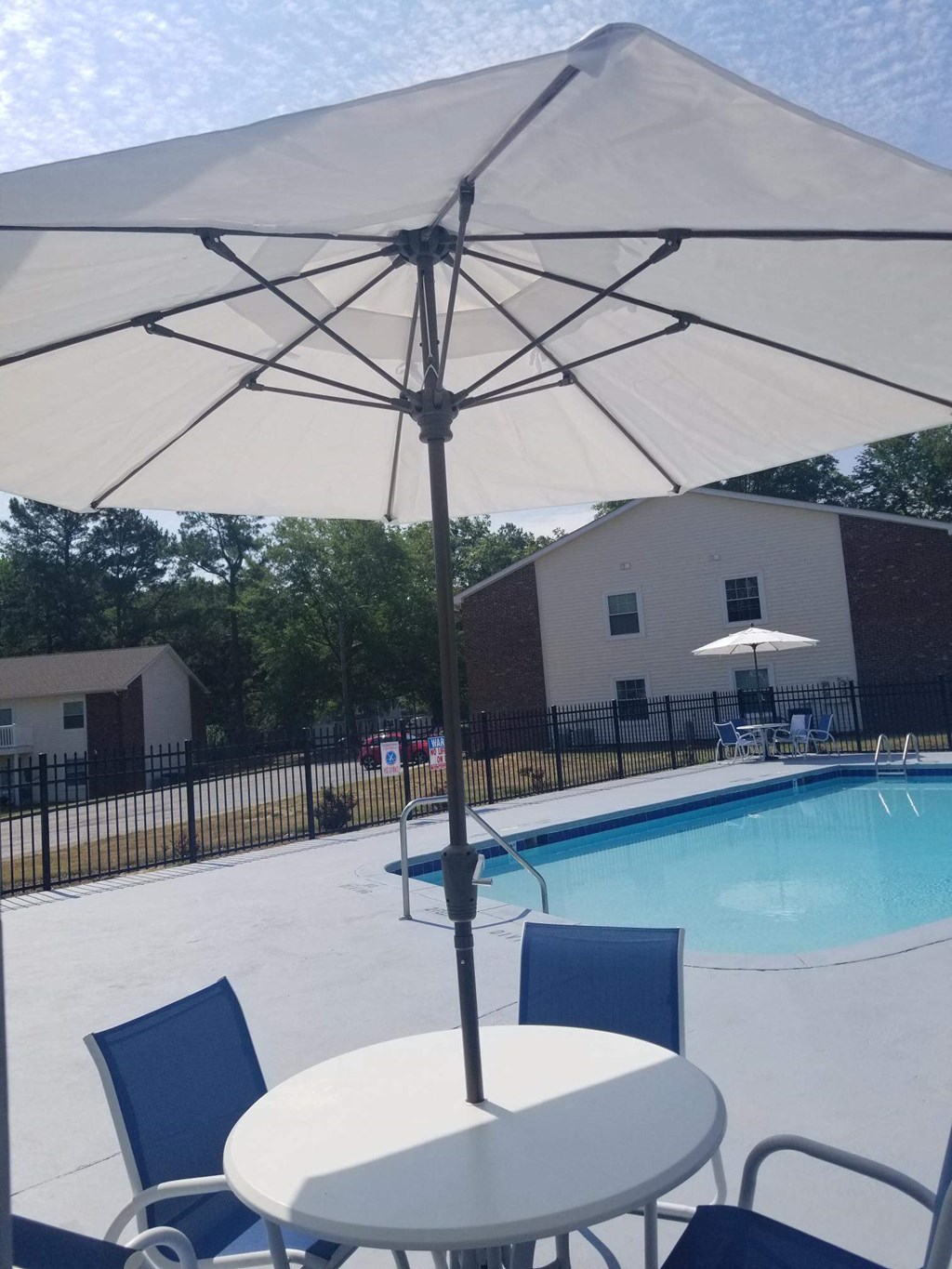 an umbrella over a table and chairs next to a swimming pool
