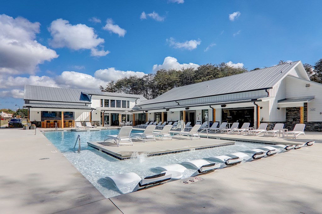 A large swimming pool with lounge chairs and a building in the background.