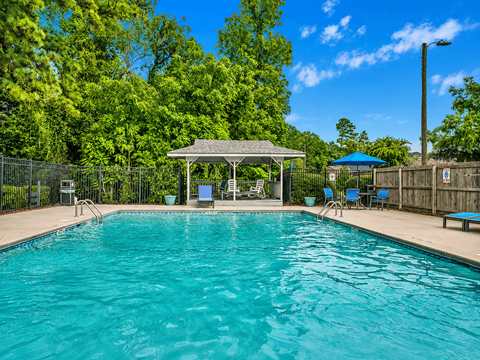 A swimming pool with a gazebo and chairs around it.