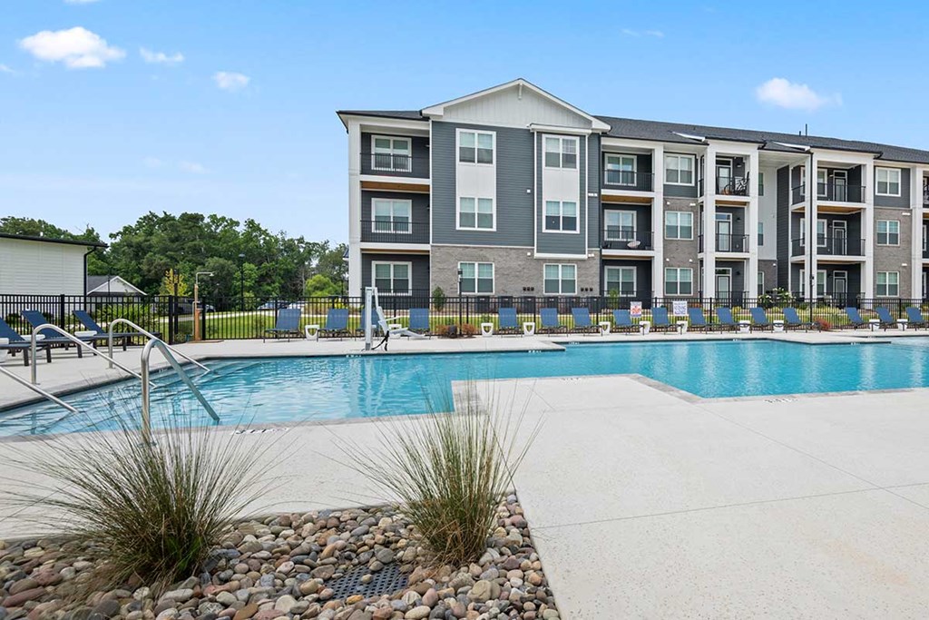 A large apartment complex with a pool in front.