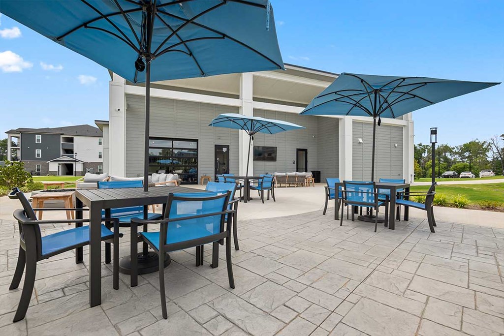 A patio with tables and chairs under umbrellas.
