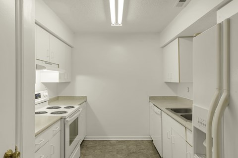 A white kitchen with a stove, sink, and cabinets.