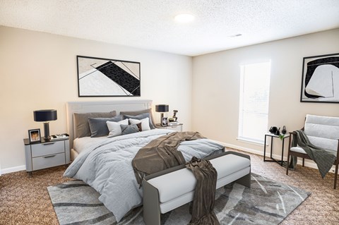 A bedroom with a large bed and a chair.