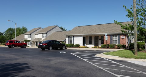 A black car is parked in a parking lot in front of a building.