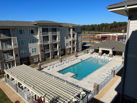 A large swimming pool is surrounded by bleachers in a residential area.