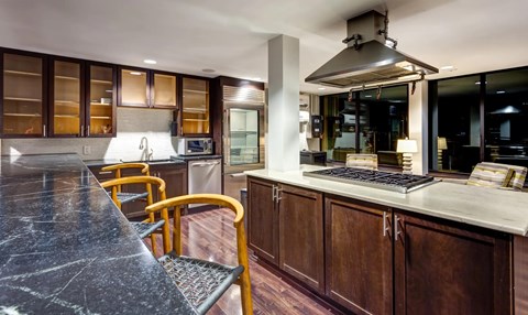 A modern kitchen with dark wood cabinets and a marble countertop.