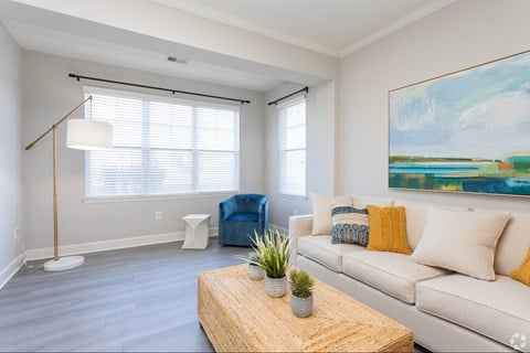 A living room with a white couch, a wooden coffee table, and a painting on the wall.