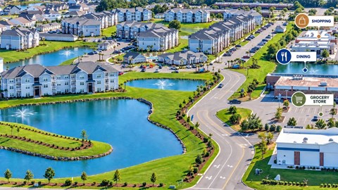 A lake in front of apartment buildings with a grocery store and a dining area nearby.