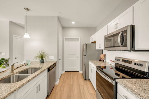 A kitchen with white cabinets and a wooden floor.
