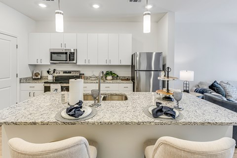 A modern kitchen with a granite countertop and white cabinets.