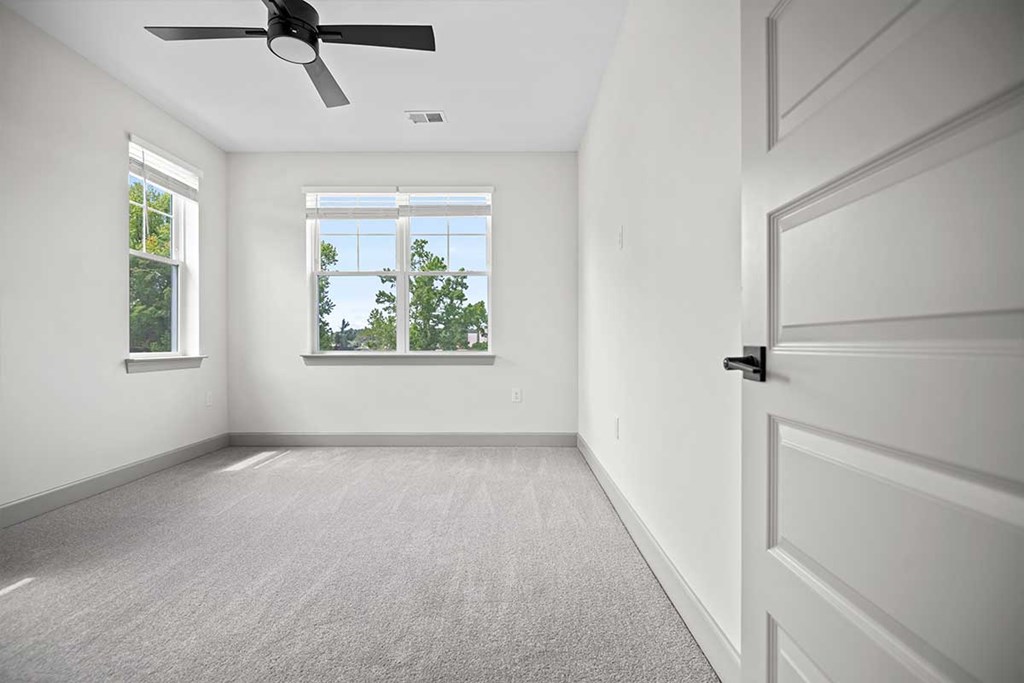 A room with a ceiling fan and a door.