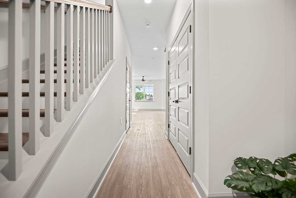 A long hallway with a wooden floor and white walls.