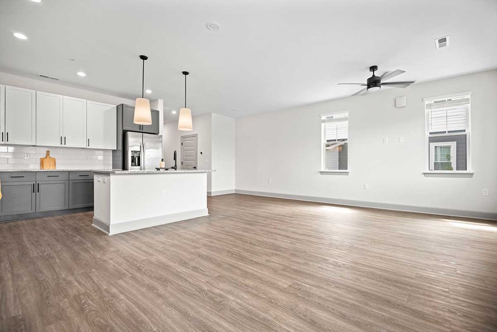 A spacious kitchen with wooden floors and white walls.