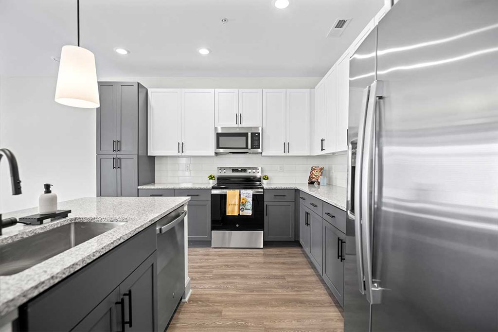 A modern kitchen with a stainless steel refrigerator and wooden floors.