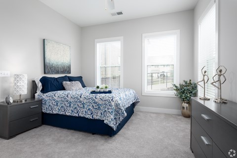 A bedroom with a bed, nightstands, and a plant.