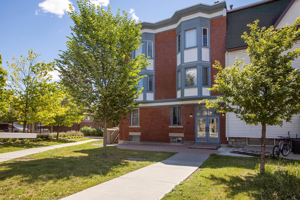 A red brick building with a green tree in front.