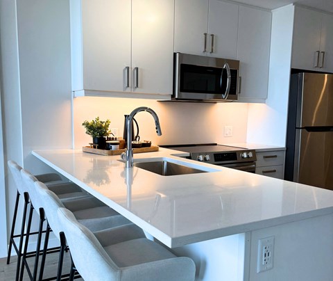 A kitchen with a white countertop and a stainless steel refrigerator.
