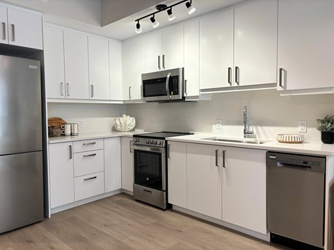 A modern kitchen with white cabinets and stainless steel appliances.