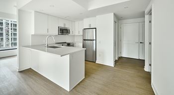 an empty kitchen with white cabinets and a stainless steel refrigerator