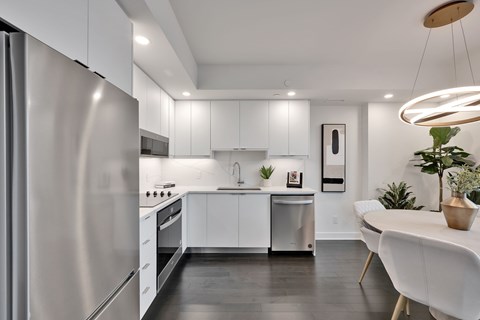 A modern kitchen with white cabinets and a stainless steel refrigerator.
