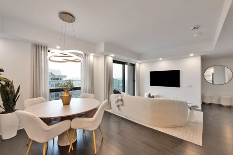 A modern dining room with a round table and white chairs.